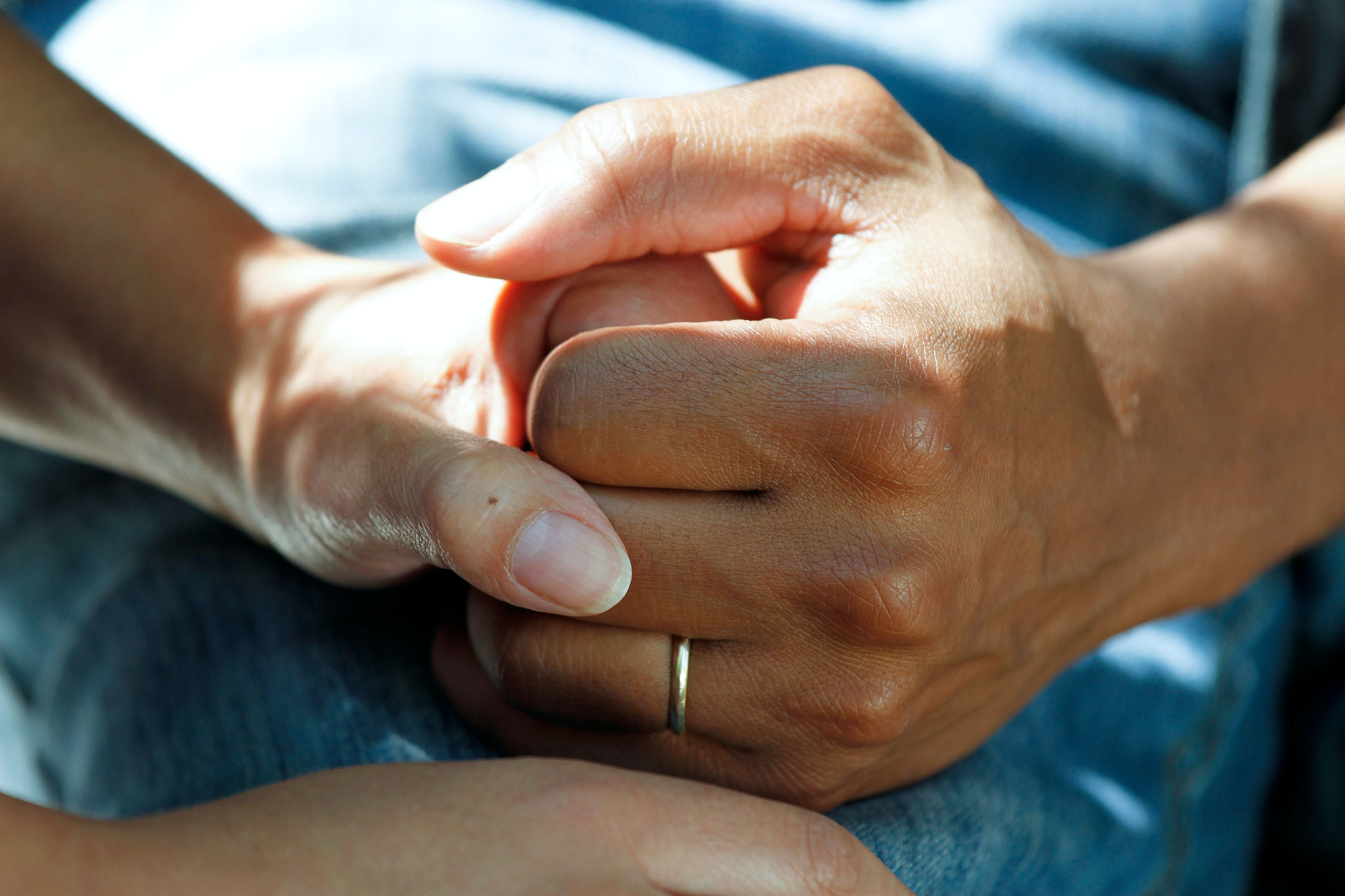 Close up image of two people holding hands, indicating support and compassion